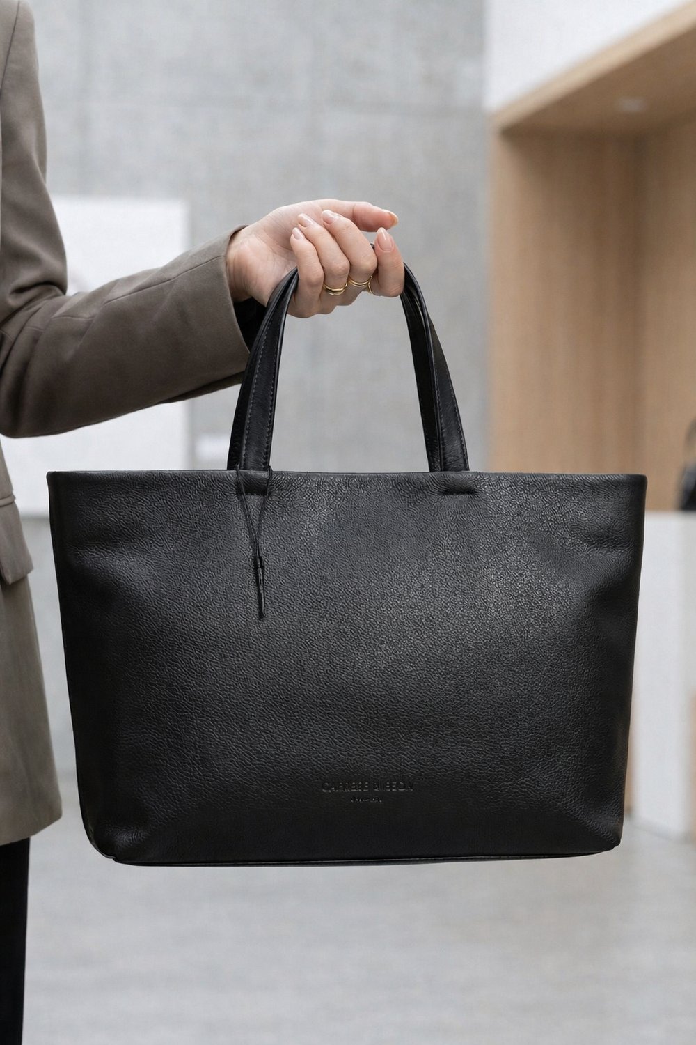 Woman holding black leather tote bag, elegant everyday handbag for office and casual use