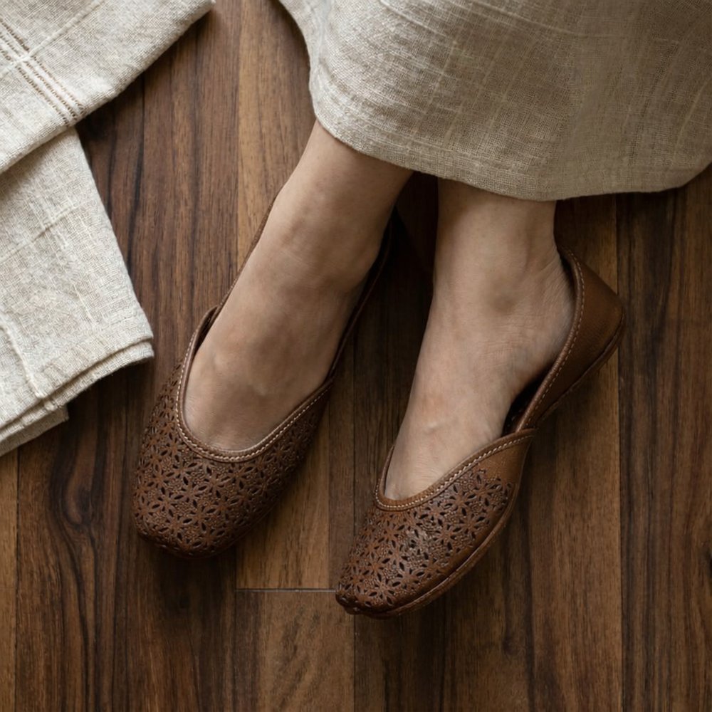 Women wearing brown leather jutti with floral cut design paired with beige ethnic outfit for a comfortable stylish look