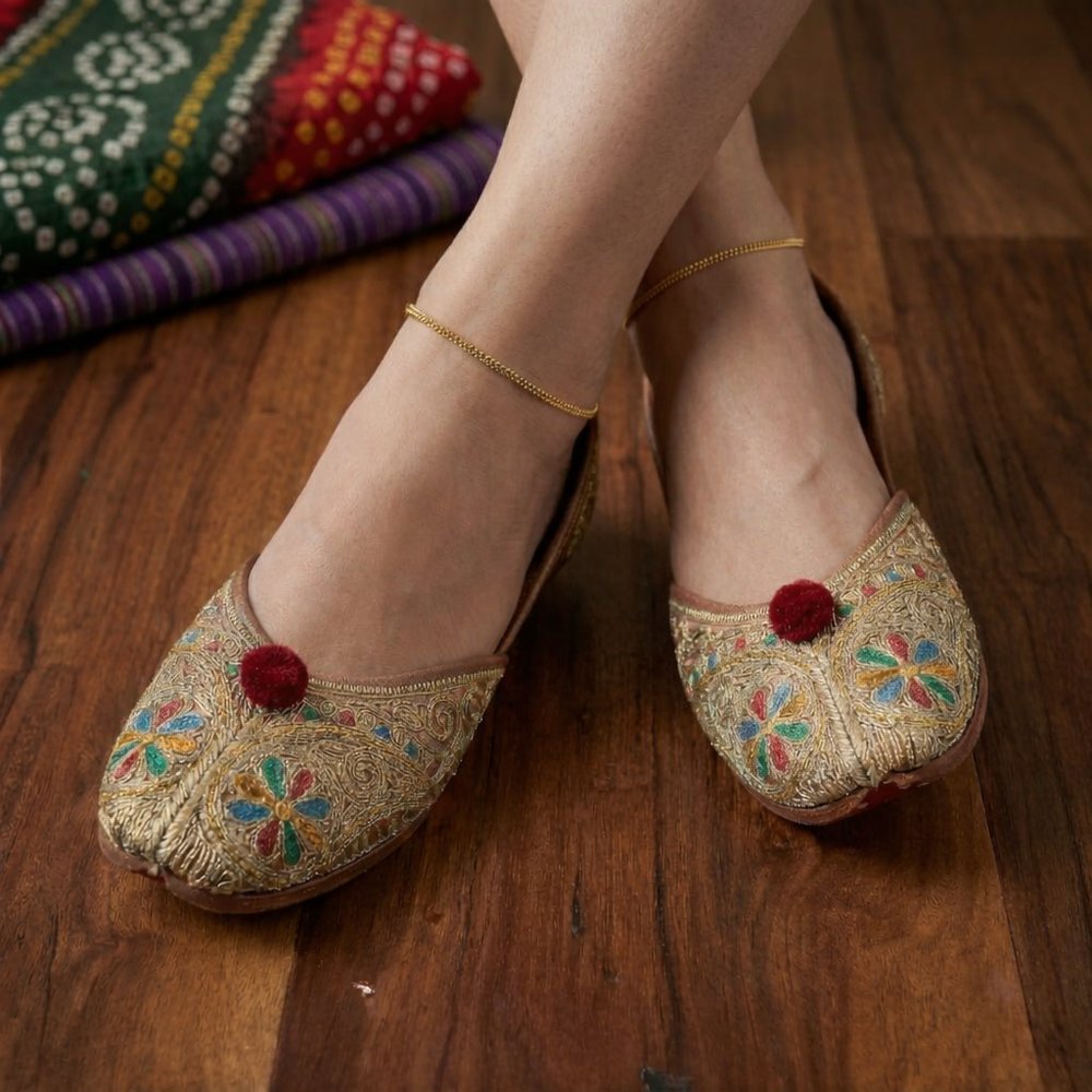High-angle shot of neutral-toned leather mojaris featuring vibrant blue, red, and green silk thread floral patterns