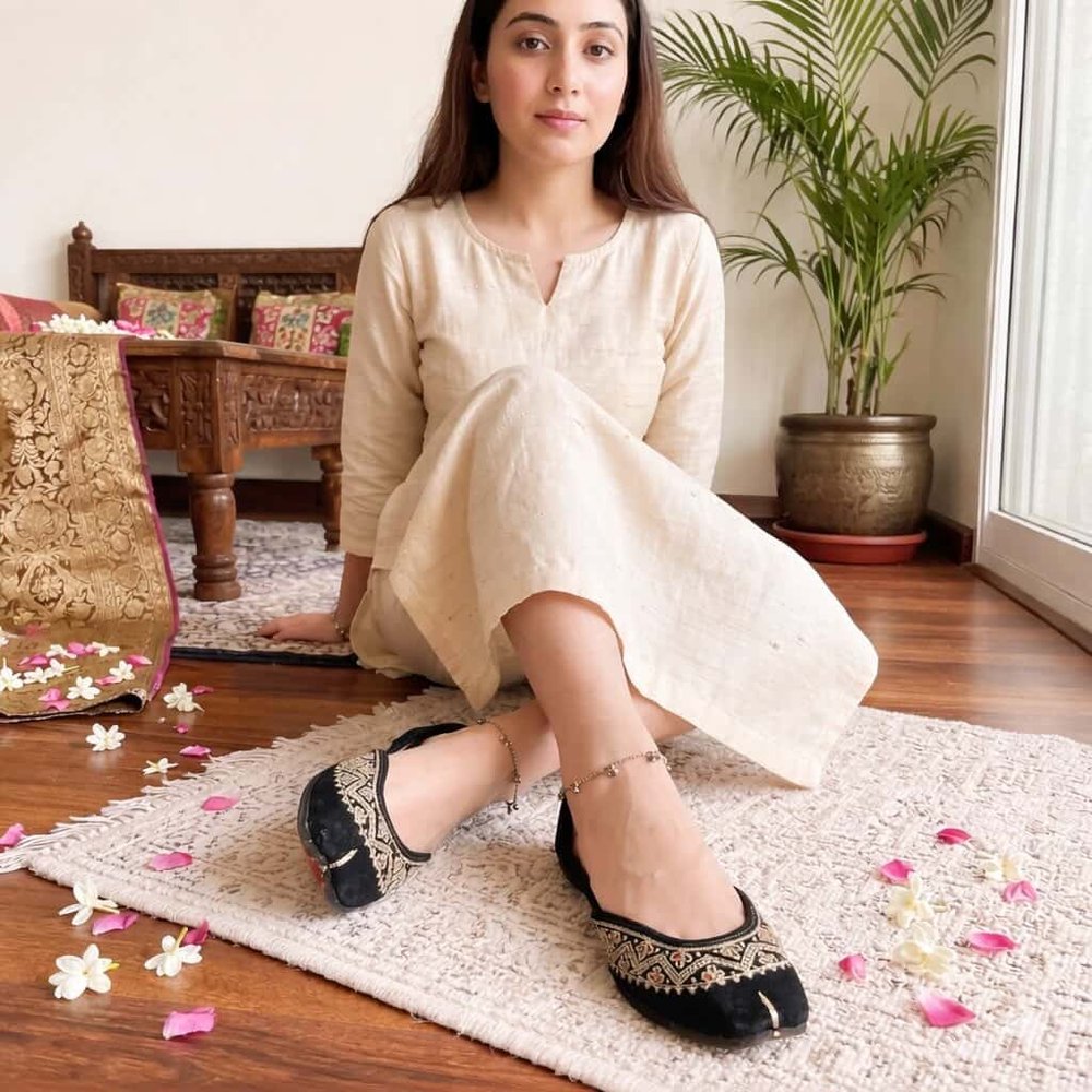 Handcrafted black embroidered jutti for women styled with ethnic outfit sitting pose