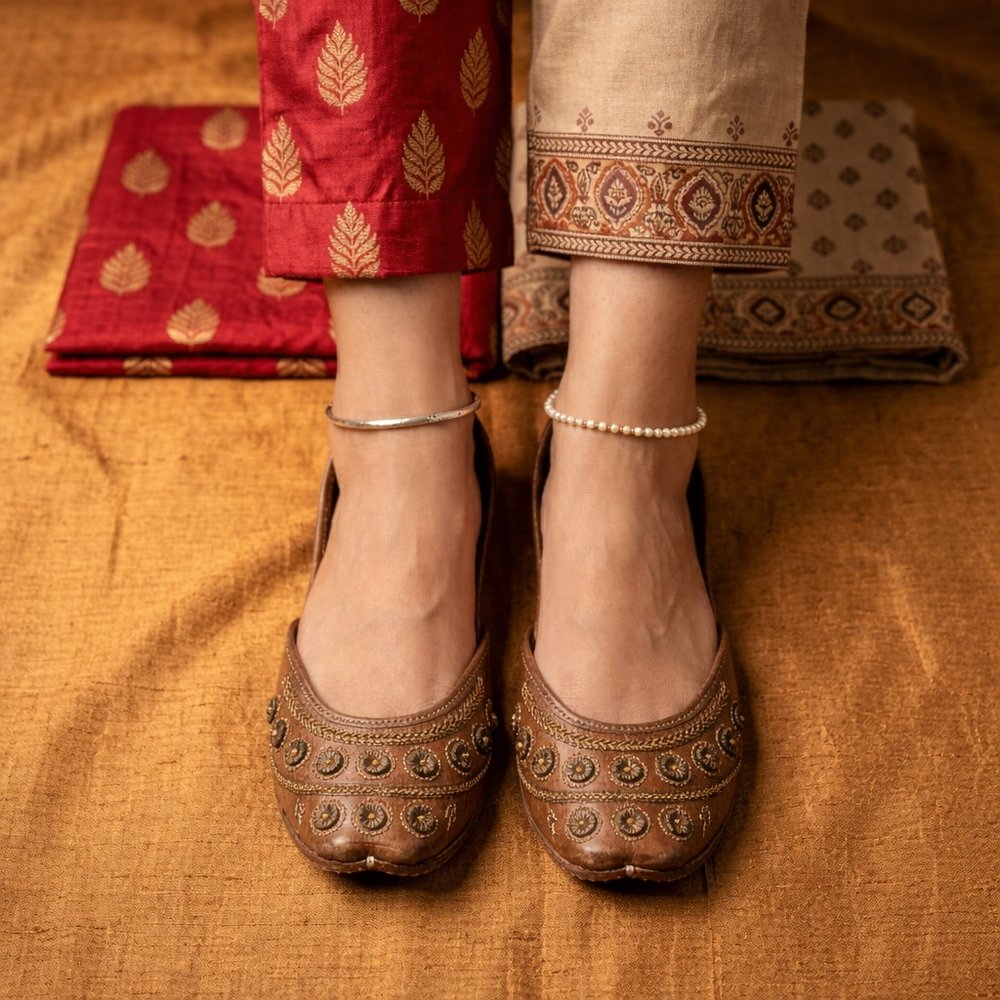Handcrafted brown leather jutti with Mughal coin design paired with traditional attire and anklets