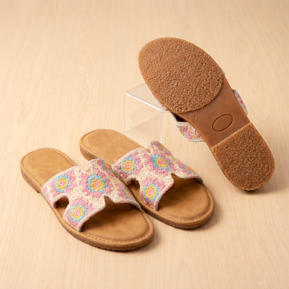 Bottom sole detail of pastel embroidered slip-on sandals showing anti-slip textured rubber sole